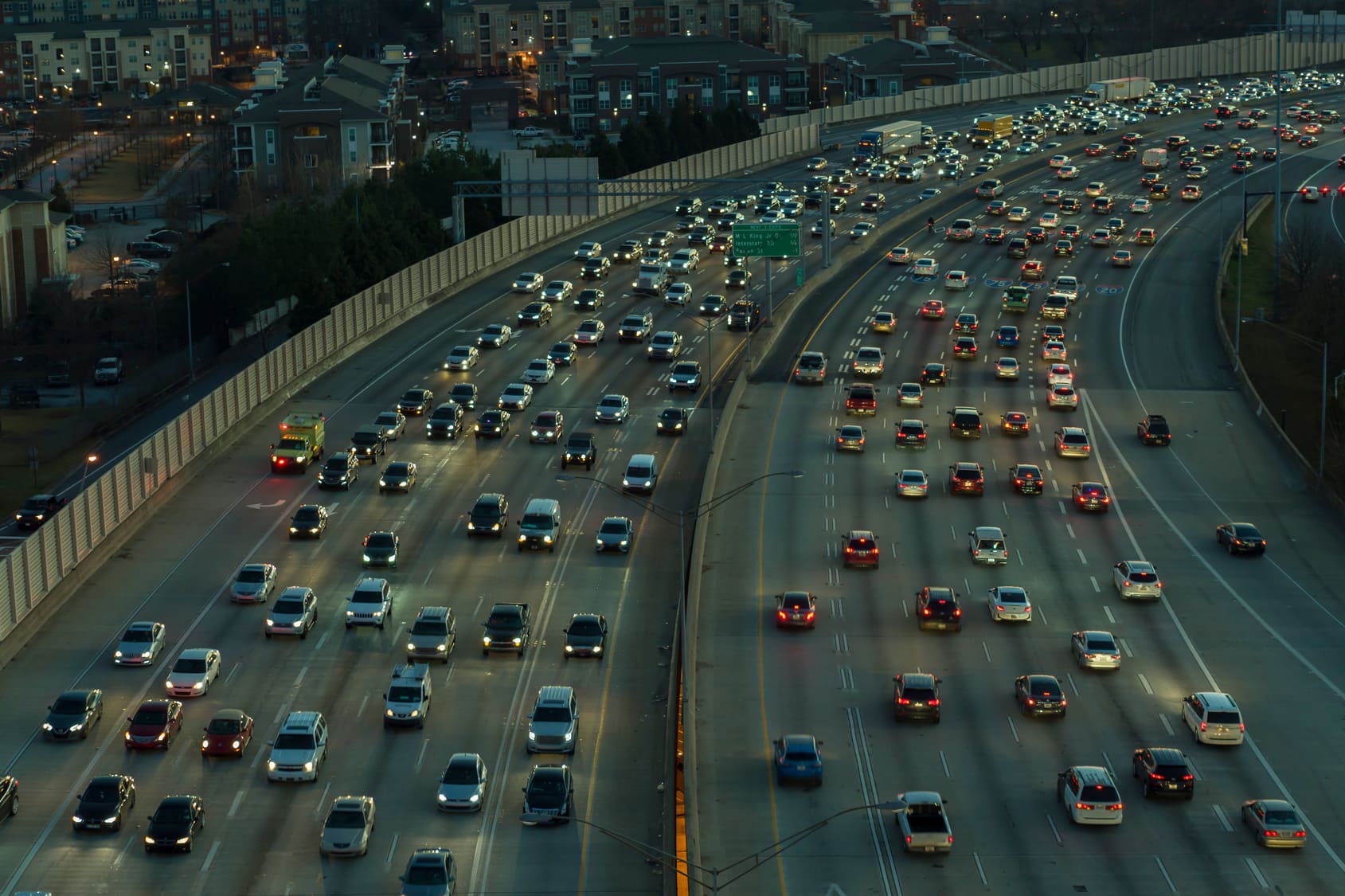 Evening traffic on I-85 in downtown Atlanta, Georgia, showing multiple lanes of cars under dusk lighting with city buildings in the background.