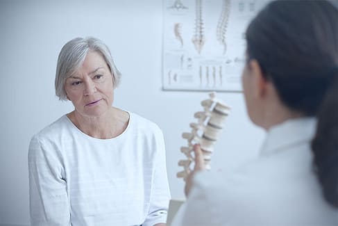 Por qué las lesiones por accidentes automovilísticos suelen provocar dolor tardío 3 Médico y paciente discutiendo la calidad de vida después de una cirugía de columna