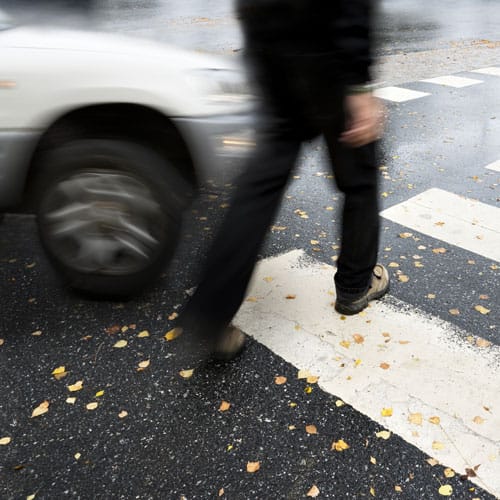 Peatón cruzando intersección urbana con tráfico vehicular