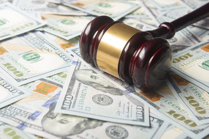 ¿Qué sucede si no puedo, o no pago, una multa en Texas? 3 Martillo encima de billetes de 100 dólares. Guía para pago una multa de tráfico en Texas.