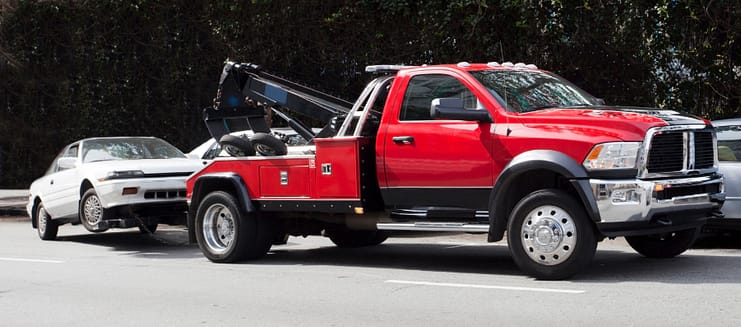 ¡Sorpresa! ¡Tu auto SE HA IDO! Grúa roja arrastrando un coche blanco que está siendo remolcado