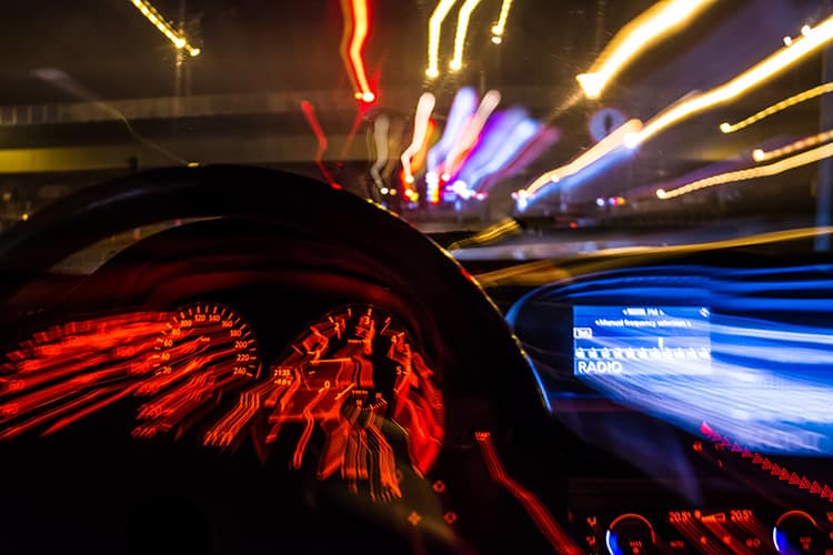 Night dashboard blur with police lights ahead, illustrating legal risks of drinking non-alcoholic beer while driving.